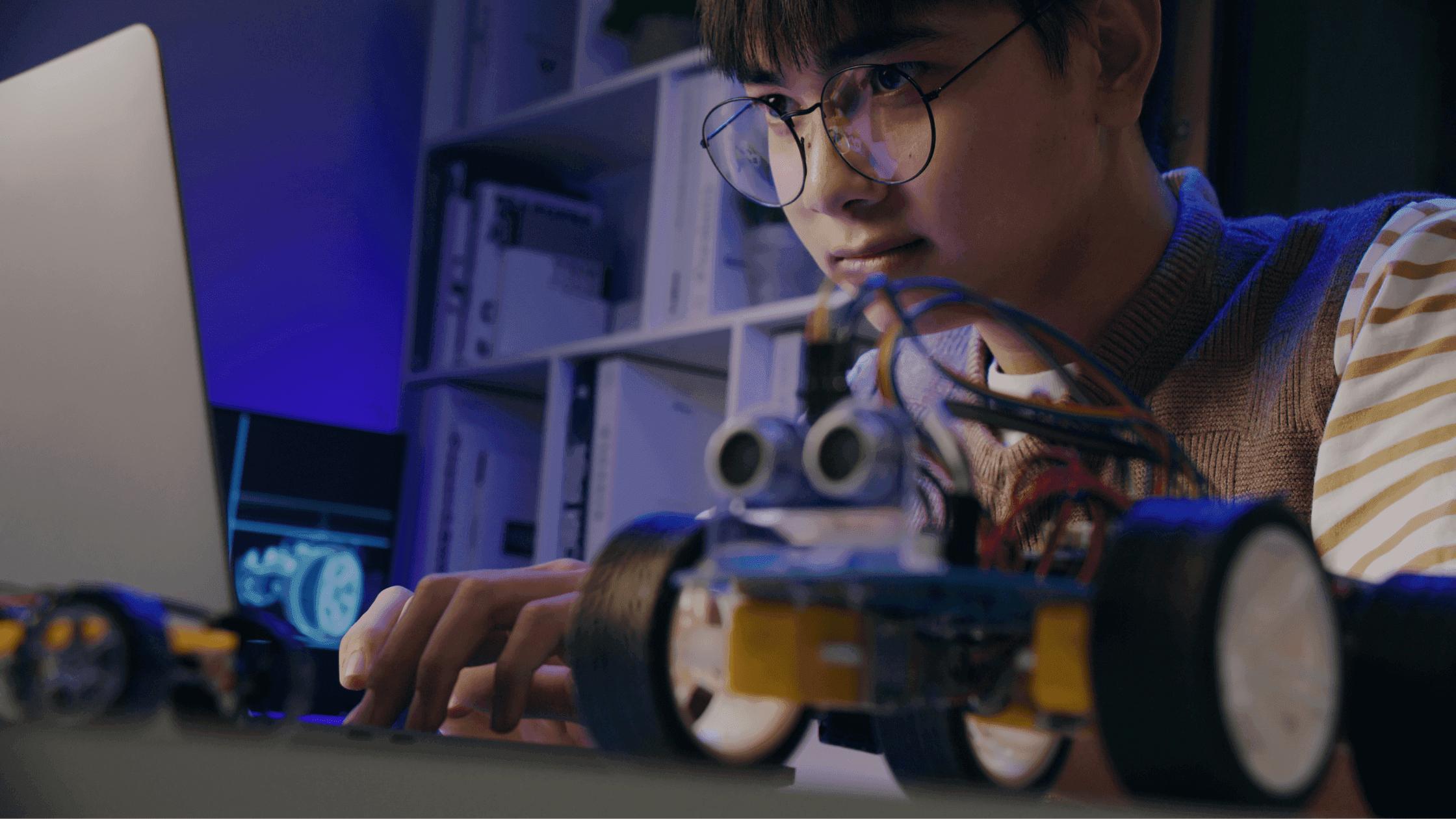 Niño investigando en la computadora junto a su robot hecho con Arduino